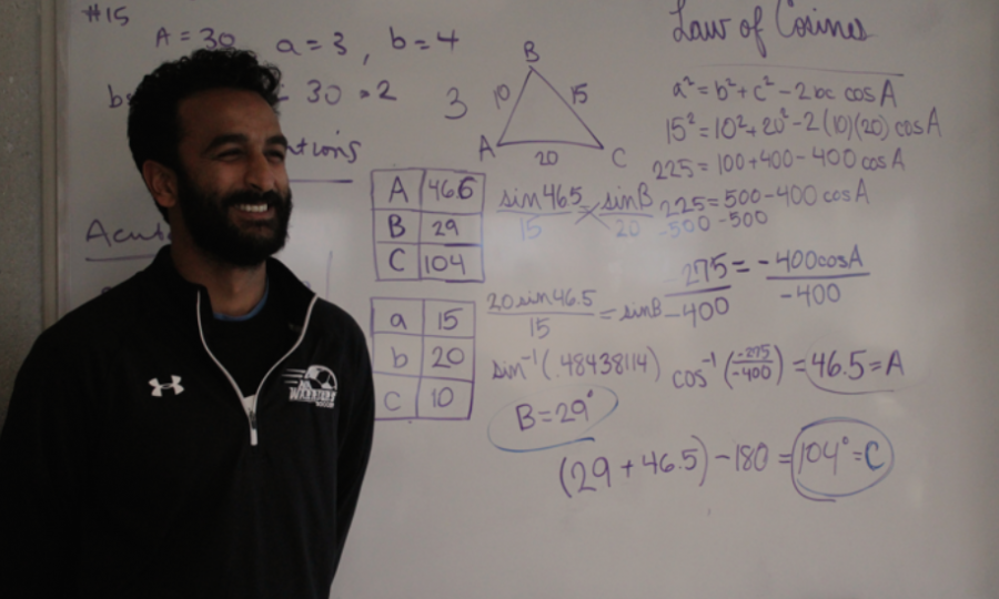 Math teacher Hemal Patel poses in front of the intricate work he displays on the board for his students. 
