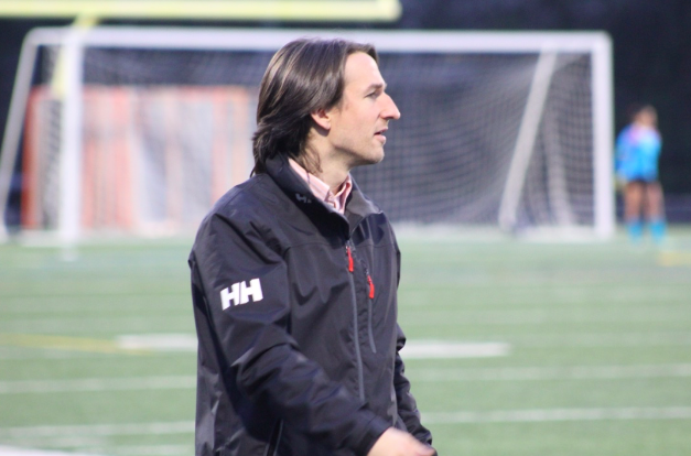 Coach Bramlett pacing the sidelines of a soccer game at Warrior Field. 