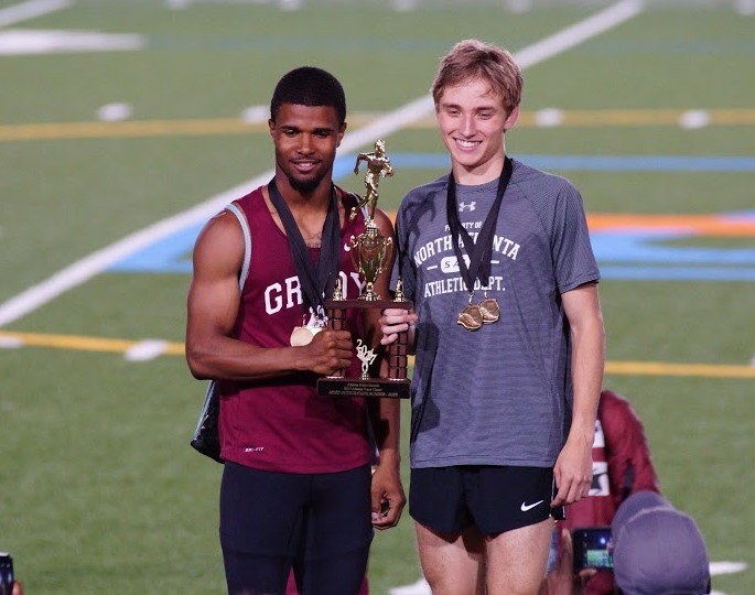 Senior Jackson Pearce hoists more trophy hardware at the APS Championships on April 25. Joining him is a Grady High competitor. 