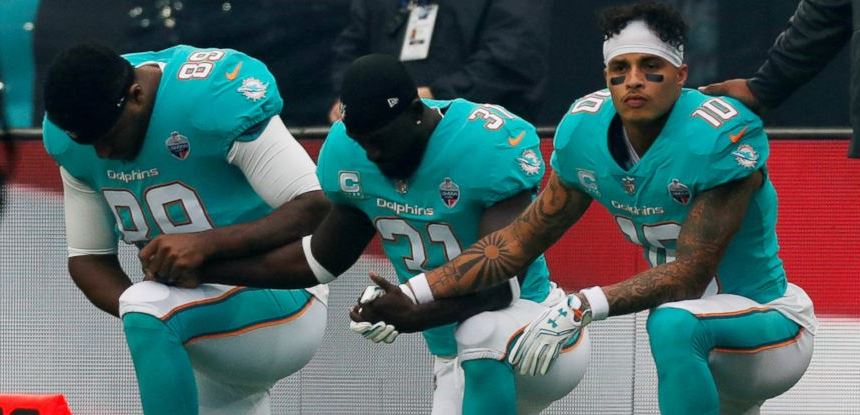 Players+from+the+Miami+Dolphins+kneel+to+make+a++statement+about+equal+treatment.+