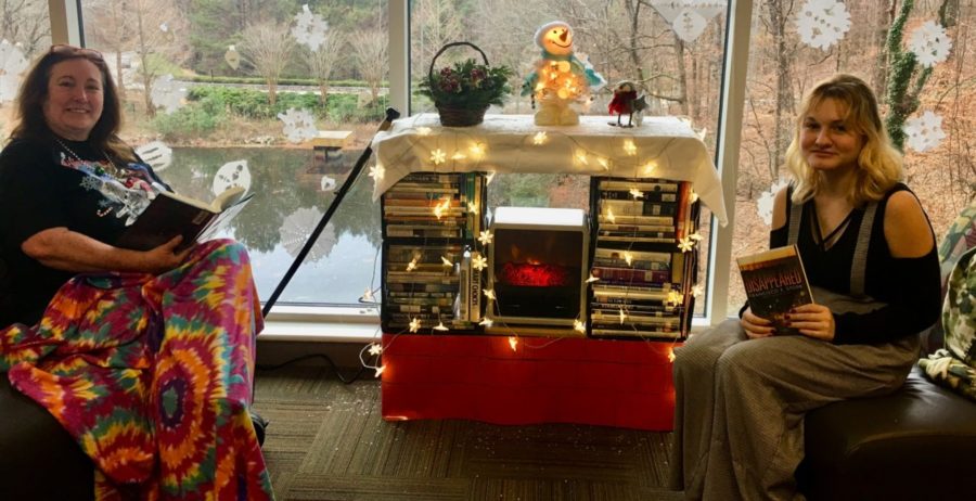 Media specialist Lori McCall and freshman Ellie Hodgson enjoy reading their books in front of the fireplace as a part of the Tome Society book club. 