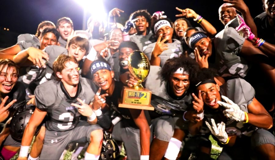 Hoco+Heaven%3A+Holding+aloft+the+WSB+Game+of+the+Week+trophy%2C+Warrior+players+celebrate+their+42-28+homecoming+game+victory+over+Northview.+Cady+Studios+%0A%0A