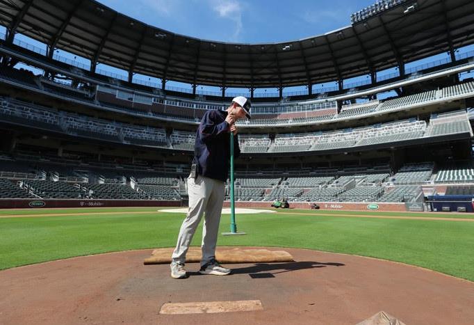 Bases Empty: An Atlanta Braves groundskeeper is the only movement in an otherwise empty Truist Park. The Coronavirus pandemic has meant a cruel springtime of no sports for sports fanatics. 
