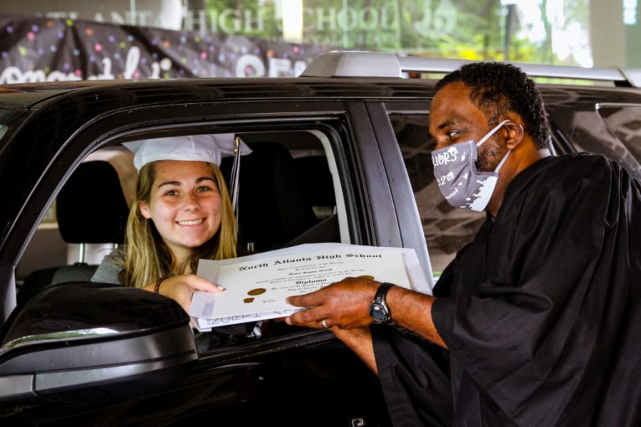 Forever Warriors: Sara Graff beams a wide smile as she received her diploma from Principal Curtis Douglass during the May 26 drive-through graduation event for the Class of 2020. 