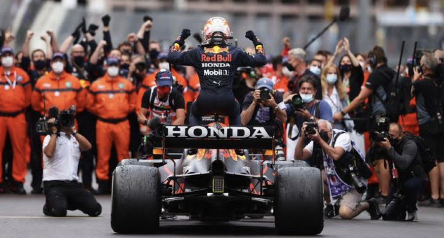 The Thrill of Victory: Max Verstappen celebrating a victory above his Red Bull car while his team celebrates.