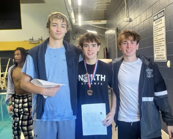 Diving into Dubs: Boys team divers (Jack Lyon, Preston Vassar, and Evan Wages) celebrate a win