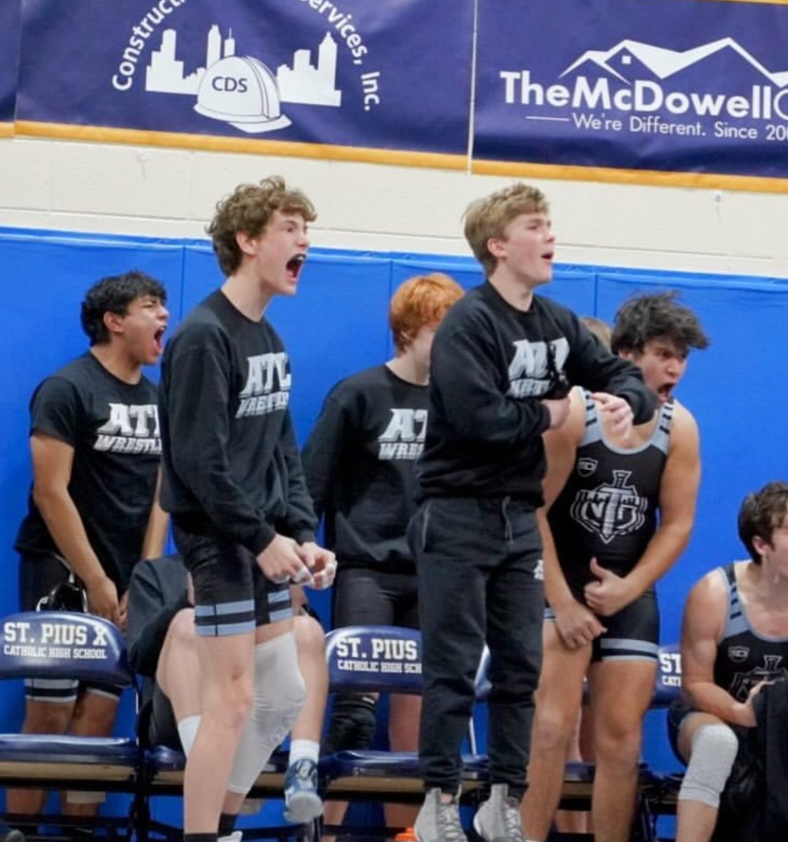 NAHS varsity wrestling stars celebrate their teammate after a massive pin.