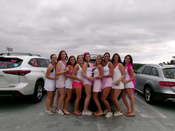 Senior dubs decked out in pink and white, posed in front of their painted cars, excited for the new school year