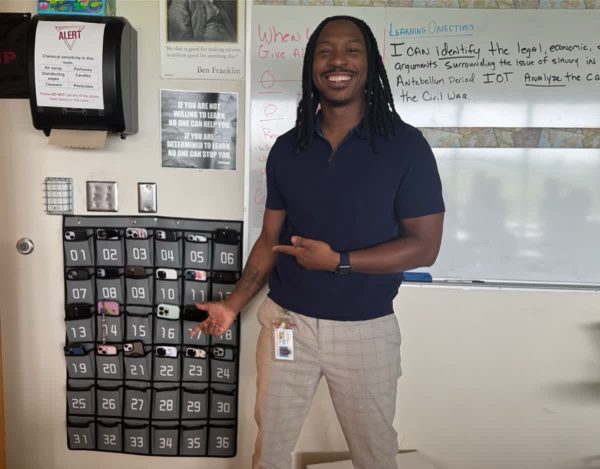 Junior IB teacher Mr McGhee standing proud next to his phone pouch. He says the new phone rule has changed  his ability to teach effectively in a positive way.