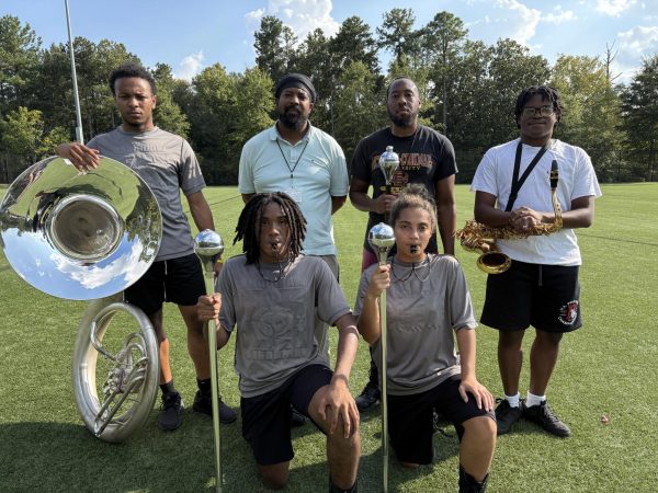 Silence before the roar: Band Director Jarius Thomas and Drum Major Coach Marcel Lewis, alongside seniors Wesley Jackson, Eva Shade, Dakota Walker, and junior Josiah Sanders.