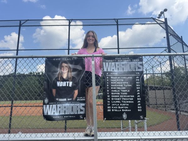 Senior Eve Heller taking in her final year of Dubs softball standing by her lone senior banner.
